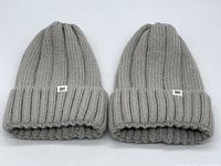 Top view of two grey wide rib knit BP brand beanies folded with label visible