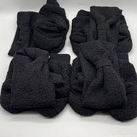 Set of four black boucle accessories including mittens and headwraps spread out.