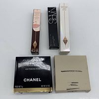 Top view showing 5 boxed cosmetic products including Charlotte Tilbury, NARS, and Chanel.