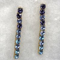 Front view of both linear drop earrings showing the gradient blue Swarovski crystals prong set in goldtone metal.