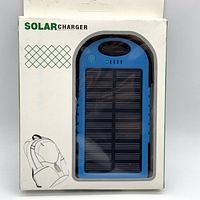 Front packaging view showing the solar charger visible through plastic window, blue and black color, solar panel visible