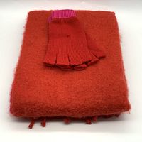 Fingerless gloves placed on folded red scarf with fringe edges