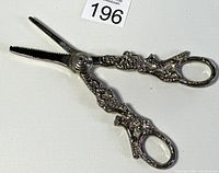Full view of the silver plated grape scissors showing ornate embossed grapevine design and finger holes