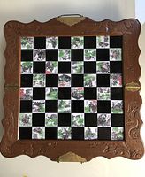 Top-down view of folded wooden chessboard showing the carved wood frame and painted inlay squares.