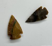 Two arrowheads displayed flat on a white background showing front sides and detailed stone textures