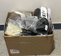 Cardboard box filled with various packaged soft items including socks and apparel.