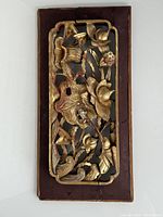 Front view of rectangular gilt wood panel with birds and flowers carved in high relief, showing crack and wear on wood frame and worn gold paint.