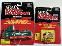 Two unopened packages showing 1997 Racing Champions 1:144 scale die cast replicas. One is green Remington Arms NASCAR stock car with trailer; second is yellow Mooneyes NHRA drag racing car on collector card.