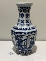 Full view of the octagonal blue and white porcelain vase showing a scene with traditional Chinese figures on one panel and detailed decorative patterns on the neck and upper body.