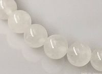 Close-up of the white jade beads showing their smooth, polished, semi-translucent white surface.