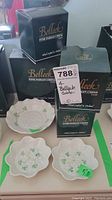 Four boxed and unboxed Belleek Fine Parian China dishes with shamrock decoration and size labels. Two 5" dishes and two 6" dishes shown with original packaging.
