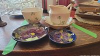 Entire lot of Belleek cream and sugar set with saucer, candy dish, and two Moorcroft plates.