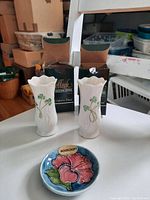 Two Belleek porcelain vases with shamrock decoration standing in front of their boxes, along with the Moorcroft small plate.