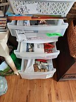 Stacked plastic drawers containing boxes, talismans, bracelets, and other small items.