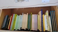 Photo showing a drawer filled with assorted books belonging to the Leprechaun Library collection in various colorful covers and sizes.