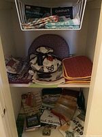 Shelf with assorted tea towels and placemats, including striped microfiber towels and chicken print towel bundle.