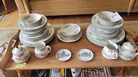 Full set of stacked Royal Doulton Campagna pattern china plates, bowls, creamers, sugar bowls, plus two small Uhlenhorst souvenir plates on wooden tray in living room