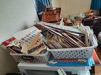 Photo showing baskets and multiple plastic trays filled with various sticker sheets and cutouts piled on a small table.
