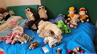 Various stuffed animals including Curious George dolls, owls, dinosaur, horse, doll on blue couch