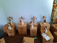 Full view of all 8 Willow Tree angel figurines arranged on their original boxes showing wire wings and carved wooden style design.