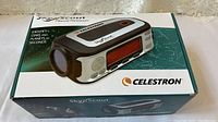 Image of the Celestron SkyScout device sealed within its original box showing product branding and image of the unit.
