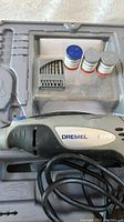 Dremel 400 XPR rotary tool in grey and black, coiled power cord visible, set in molded plastic case.