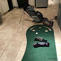 Full view of the golf bag, putting green mat, chipping net, and two golf club head covers.