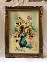 Frontal view of floral oil painting in carved gilt wood frame