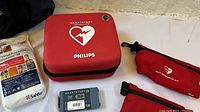 Red Philips HeartStart zippered carrying case and gray SMART Pads cartridge on white surface
