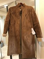Front view of Ralph Lauren women's suede coat hanging on wooden hanger showing medium size and knee length with visible cuff fleece lining.