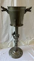 Full view of the pewter ice bucket on its tall decorative stand featuring dragon motif.