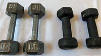 Photo showing one pair of hexagonal metal dumbbells weighing 10 pounds each, and one pair of smaller black neoprene hand weights weighing 8 pounds each