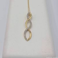 Front view of pendant showing twisted double-loop design with half pave-set diamonds and half polished gold