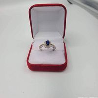 Ring displayed in red and white jewelry box on white surface