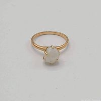 Top view of the 14k yellow gold ring with white pearl on a plain white background.