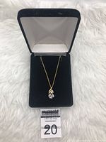 Photo of gold over sterling silver pendant necklace with opal stone hanging from gold-colored chain, displayed in black jewelry box on white fur background.