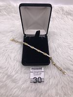 Photo of the gold over sterling silver cubic zirconia bracelet inside black jewelry box on white surface showing overall style and condition.