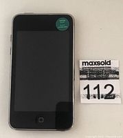 Front view of black Apple iPod Touch with screen off, home button and green sticker indicating device is wiped.