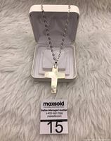 Sterling silver chain necklace with mother of pearl cross pendant displayed in a white jewelry box on a white furry surface.