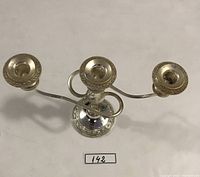 Top angled view of silverplated 3-arm candelabra showing candle holders, central stem, and ornate base