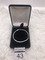 Bracelet arranged in a closed circular form inside jewelry box to show overall shape and presentation.