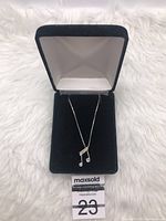 Sterling silver music note pendant necklace with diamonds displayed in a black velvet jewelry box on a white surface.