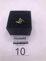 Front view of sterling silver ring with green yellow stone in black presentation box with auction lot number 10