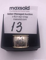 Front view of wide sterling silver ring with floral engraving and rope edge detail.