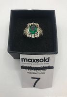 Front view of sterling silver ring with green faceted oval stone on black felt inside black box.