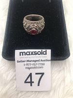 Front angle of sterling silver ring with red stone and filigree, shown in black box