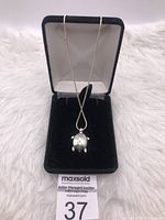 Front view of sterling silver turtle pendant necklace displayed in black jewelry box on fur surface.