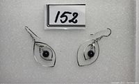 Pair of women's silver earrings with central black bead on white foam background, showing front view.