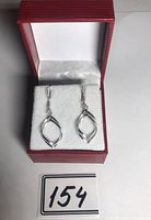 Pair of silver twisted loop drop earrings displayed in red jewelry box with white satin interior.