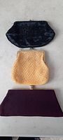 Photo showing the three ladies pocket books/purses: a black beaded floral design purse, a golden-yellow mesh purse, and a deep purple fabric purse.